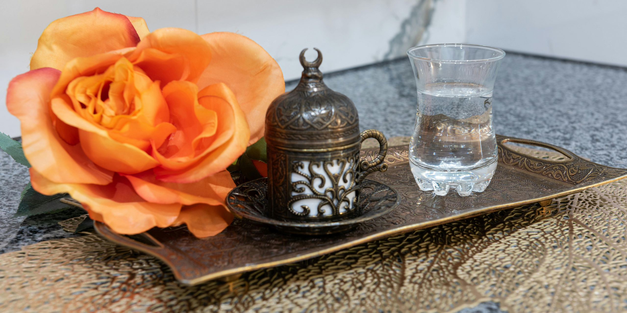 Blume mit türkischer Teetasse und Glas Wasser